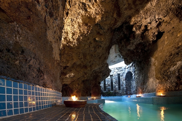 A natural rock formation with a pool and tiled walls.