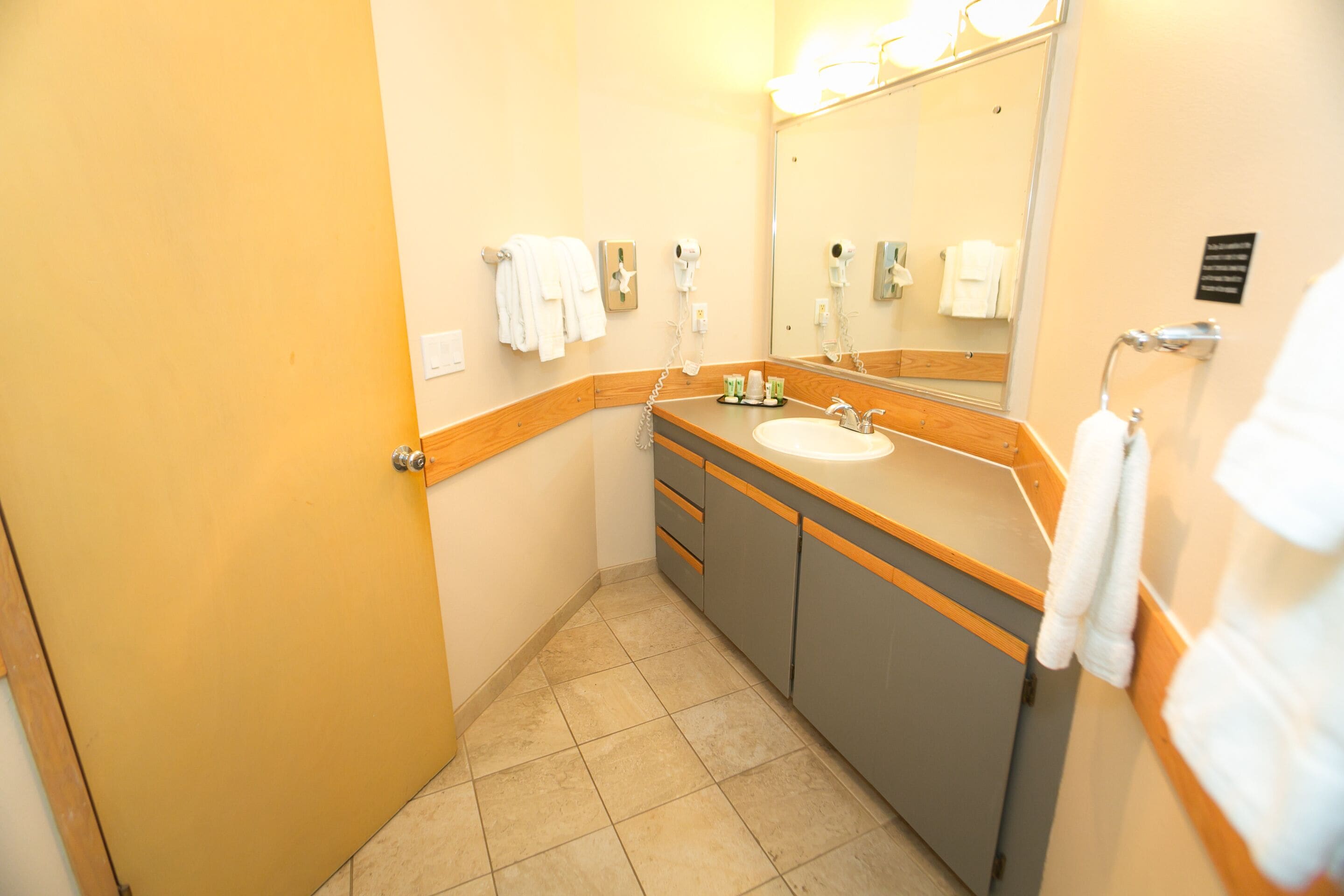 Ein kleines Badezimmer mit Waschbecken, Spiegel und Handtuchhalter.