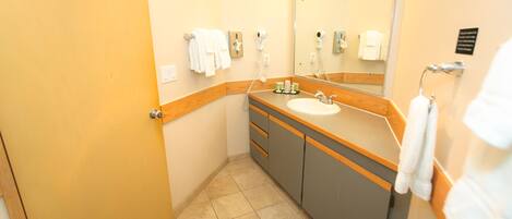 Ein kleines Badezimmer mit Waschbecken, Spiegel und Handtuchhalter.