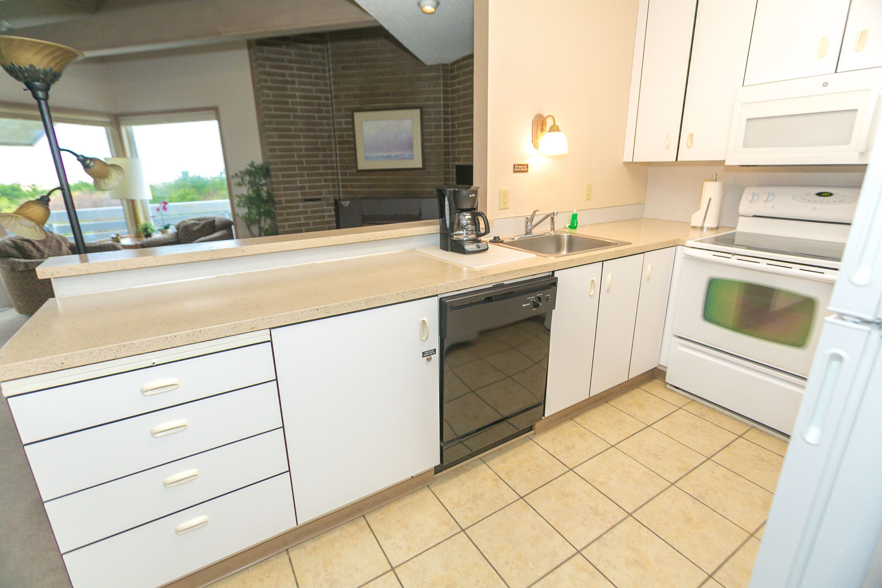 A kitchen with white cabinets, a dishwasher, a stove, and a coffee maker.