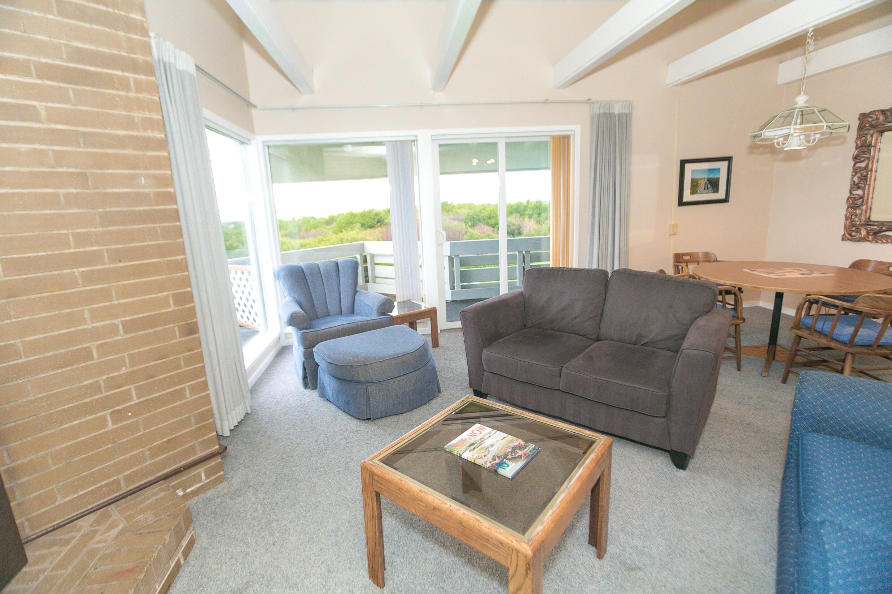 Ein Wohnzimmer mit Sofa, Hocker und Couchtisch, ein Esstisch mit Stühlen und ein Balkon mit Aussicht.
