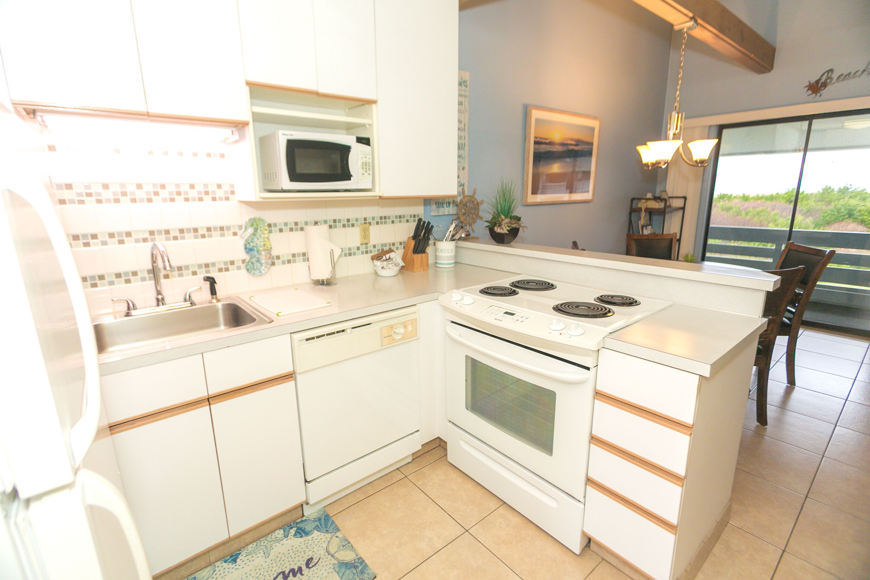 A kitchen with white cabinets, a microwave, a stove, and a sink.