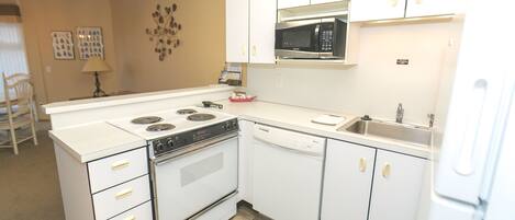 A kitchen with white cabinets, a microwave, a dishwasher, and a stove.