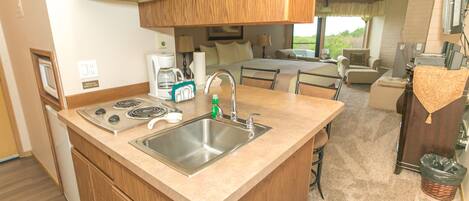 A compact kitchen with a sink, stove, and wooden cabinets.