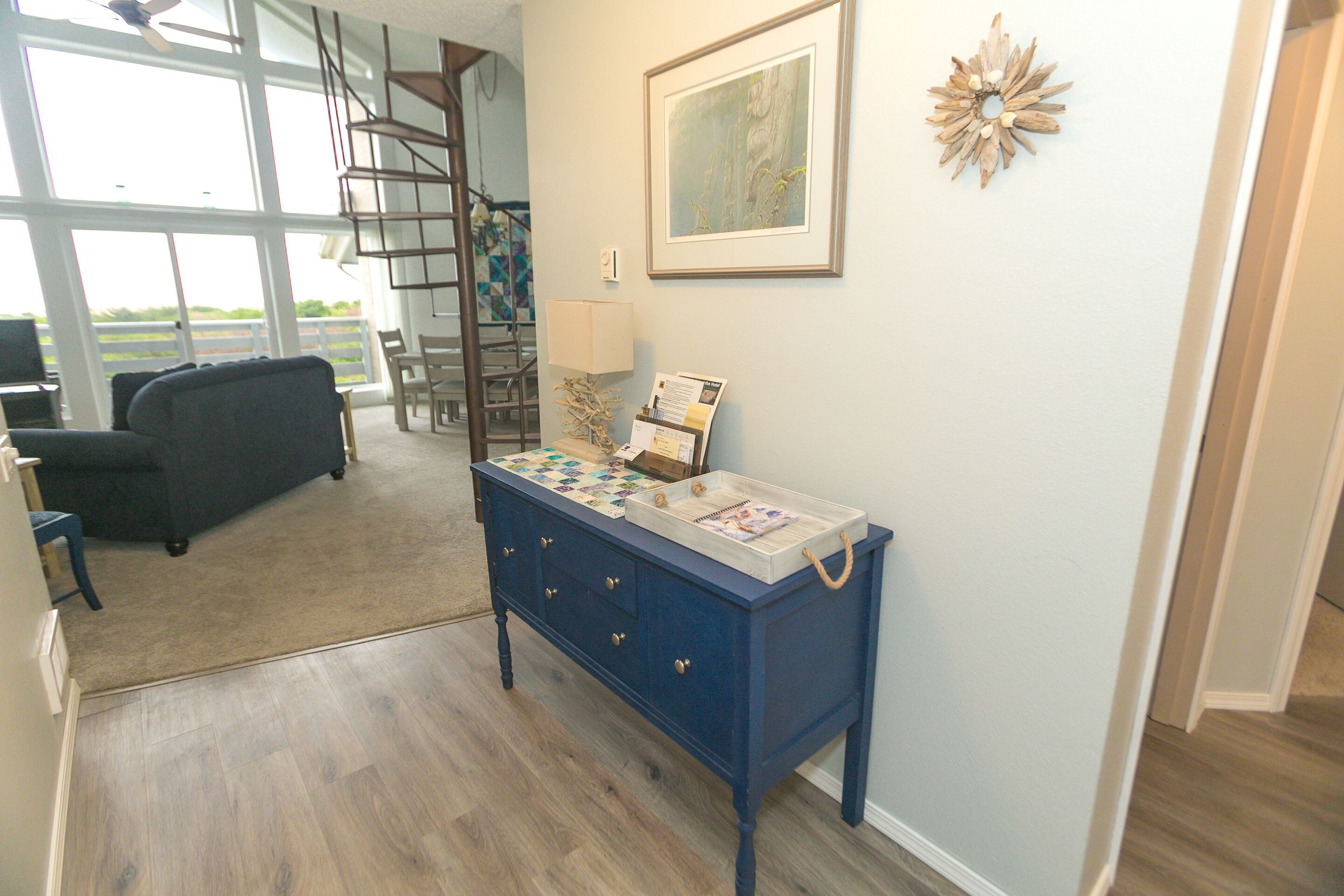 A room with a blue dresser, a ladder, a chair, and a large window.