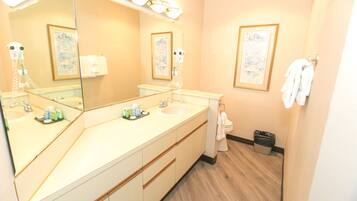 A bathroom with a double sink, a large mirror, and framed artwork on the walls.