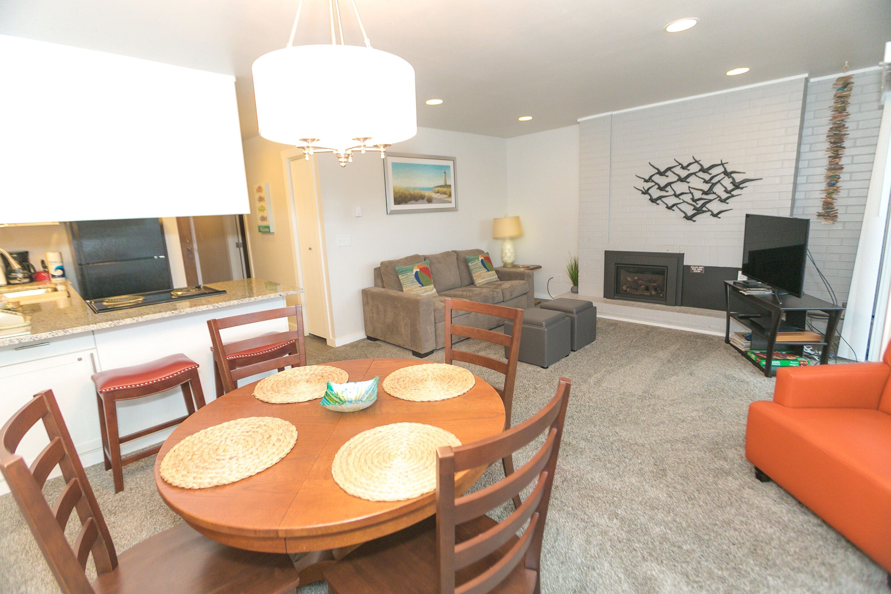 A modern living room with a dining area, a kitchen, and a fireplace.