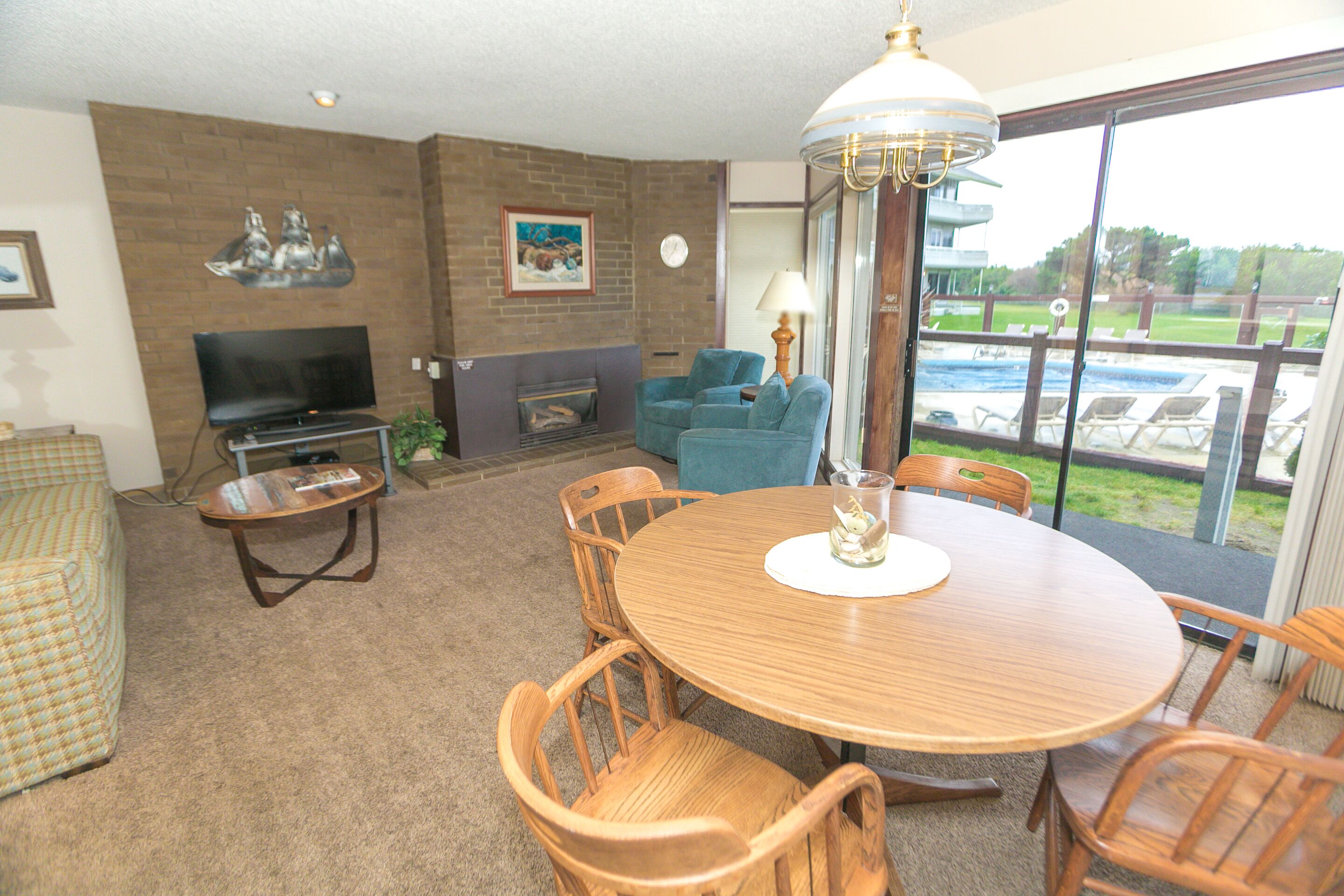 A living room with a wooden dining table, chairs, a TV, and a fireplace.