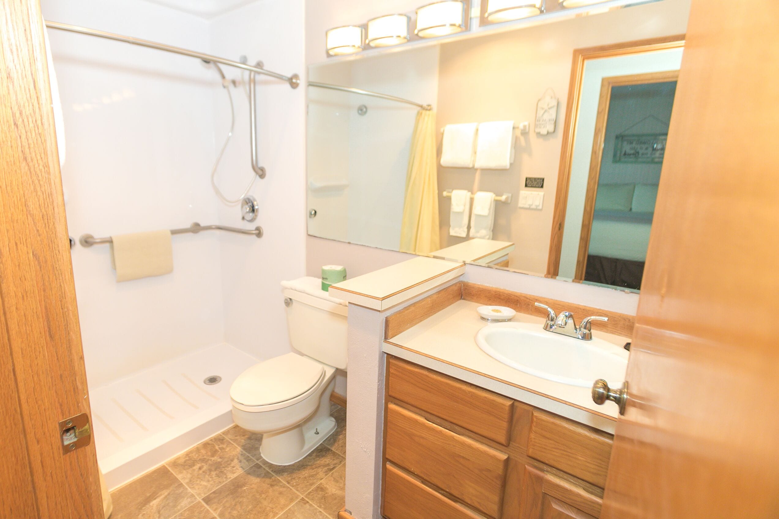 Baño con ducha, inodoro, lavabo y armarios de madera.