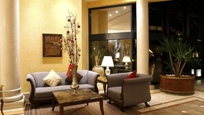 A lobby with a sofa, armchairs, a coffee table, and a potted plant. - Hotel Concorde Les Berges du Lac (Tunis)