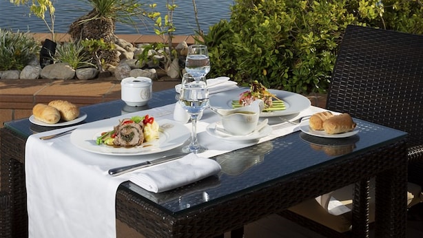 A table set for a meal with a view of the sea and mountains in the background. - Hotel Concorde Les Berges du Lac (Tunis)