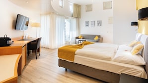 A modern hotel room with a bed, desk, chair, and a TV mounted on the wall. - Hotel Schatzmann (Triesen)