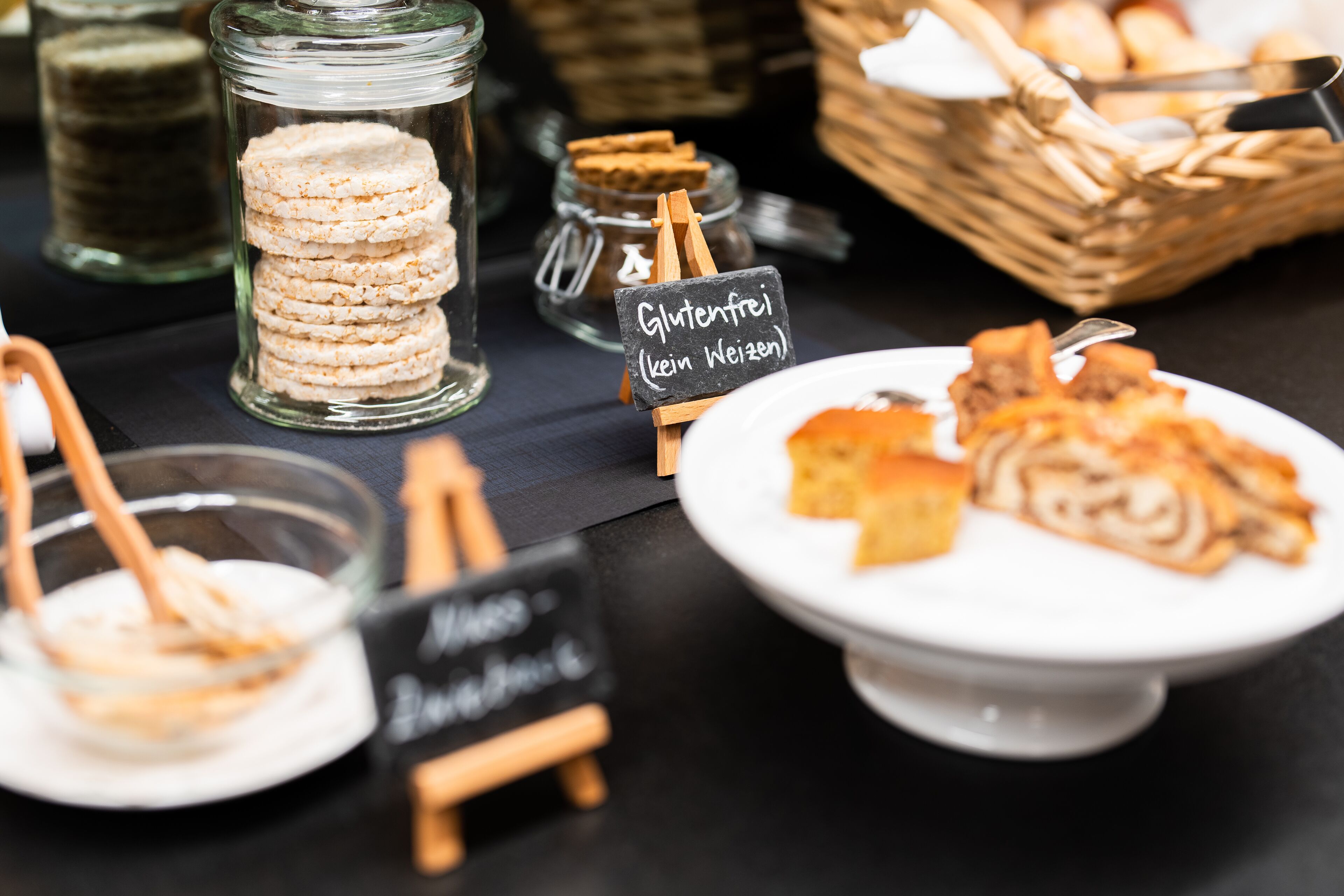 A buffet table with various food items, including cookies and pastries, with labels indicating they are gluten-free.