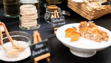 A buffet table with various food items, including cookies and pastries, with labels indicating they are gluten-free.