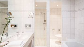 A modern bathroom with a walk-in shower, a bathtub, and a vanity with two sinks.
