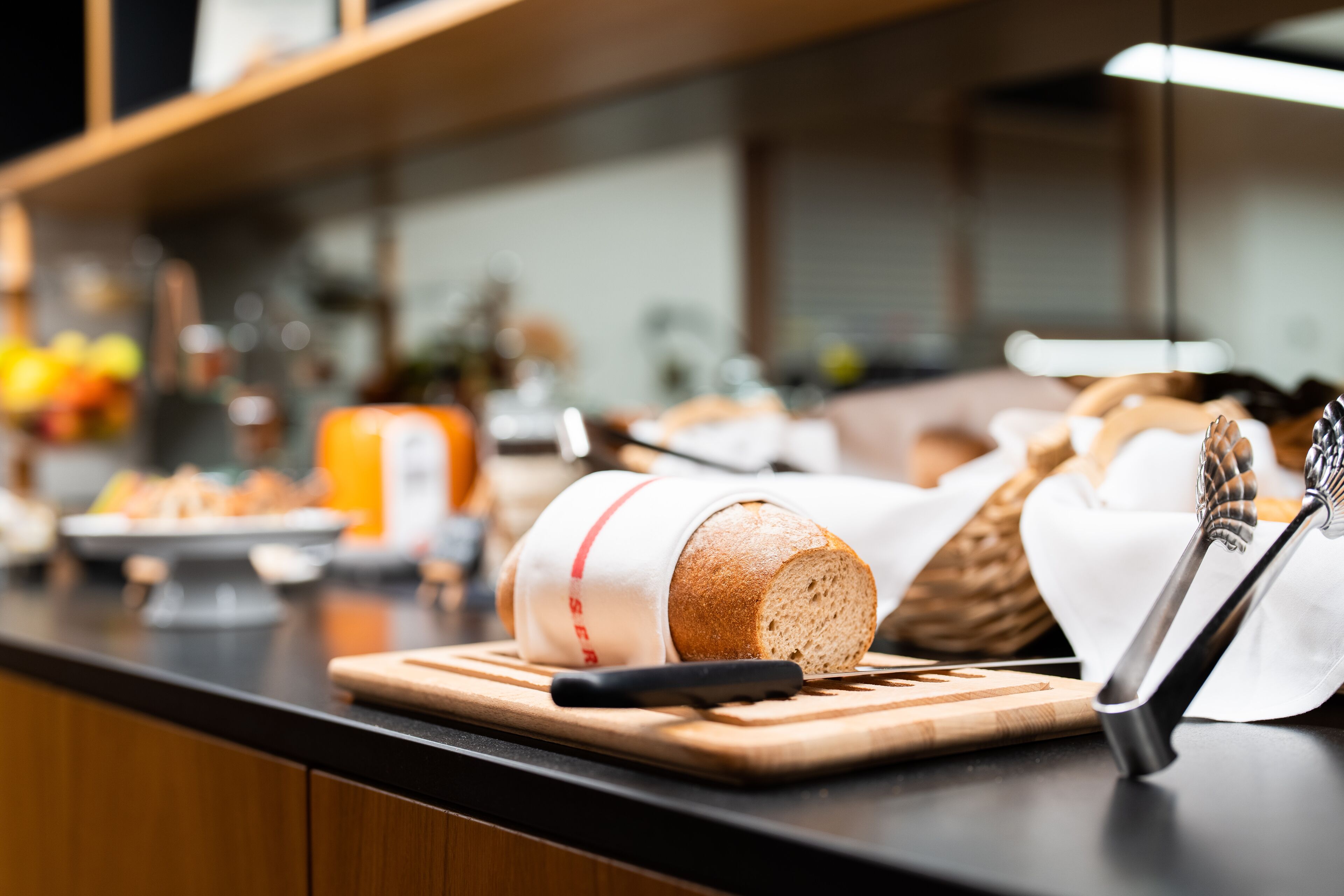 A kitchen counter with a loaf of bread, a knife, and a whisk.