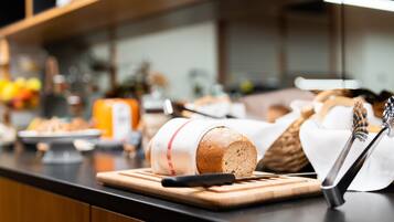 A kitchen counter with a loaf of bread, a knife, and a whisk.