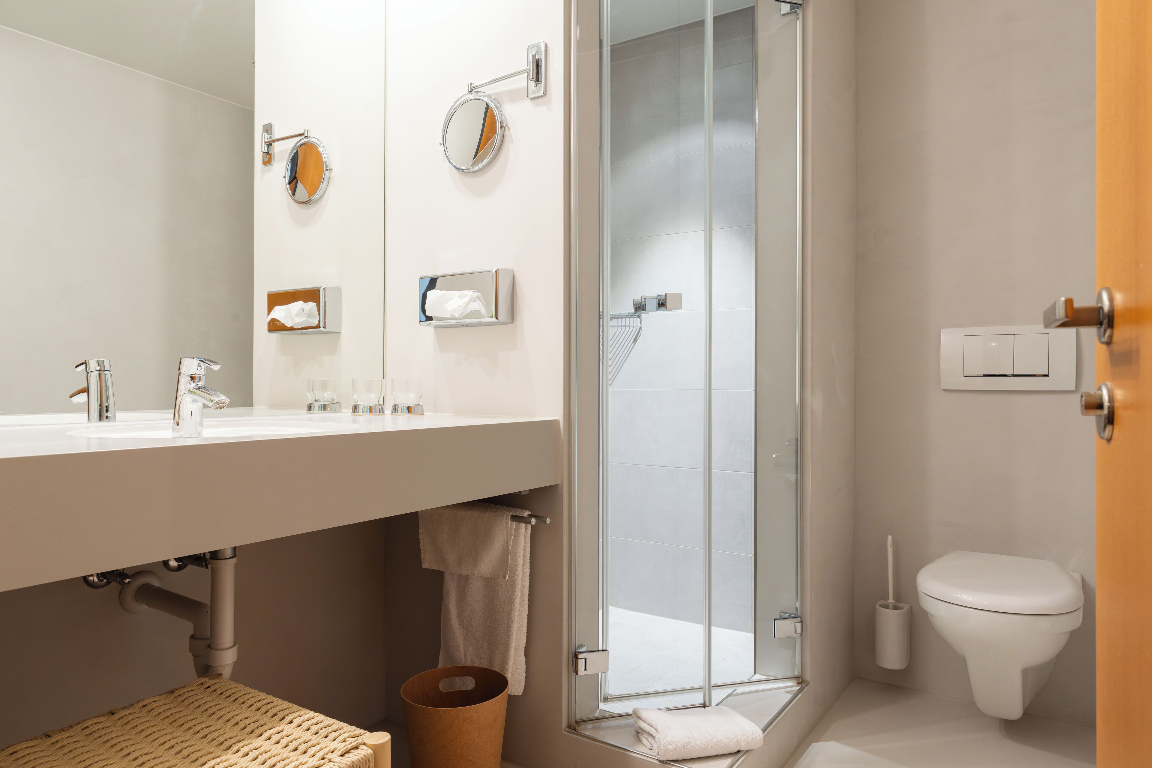 A modern bathroom with a glass shower enclosure, a toilet, and a sink with a towel rack.