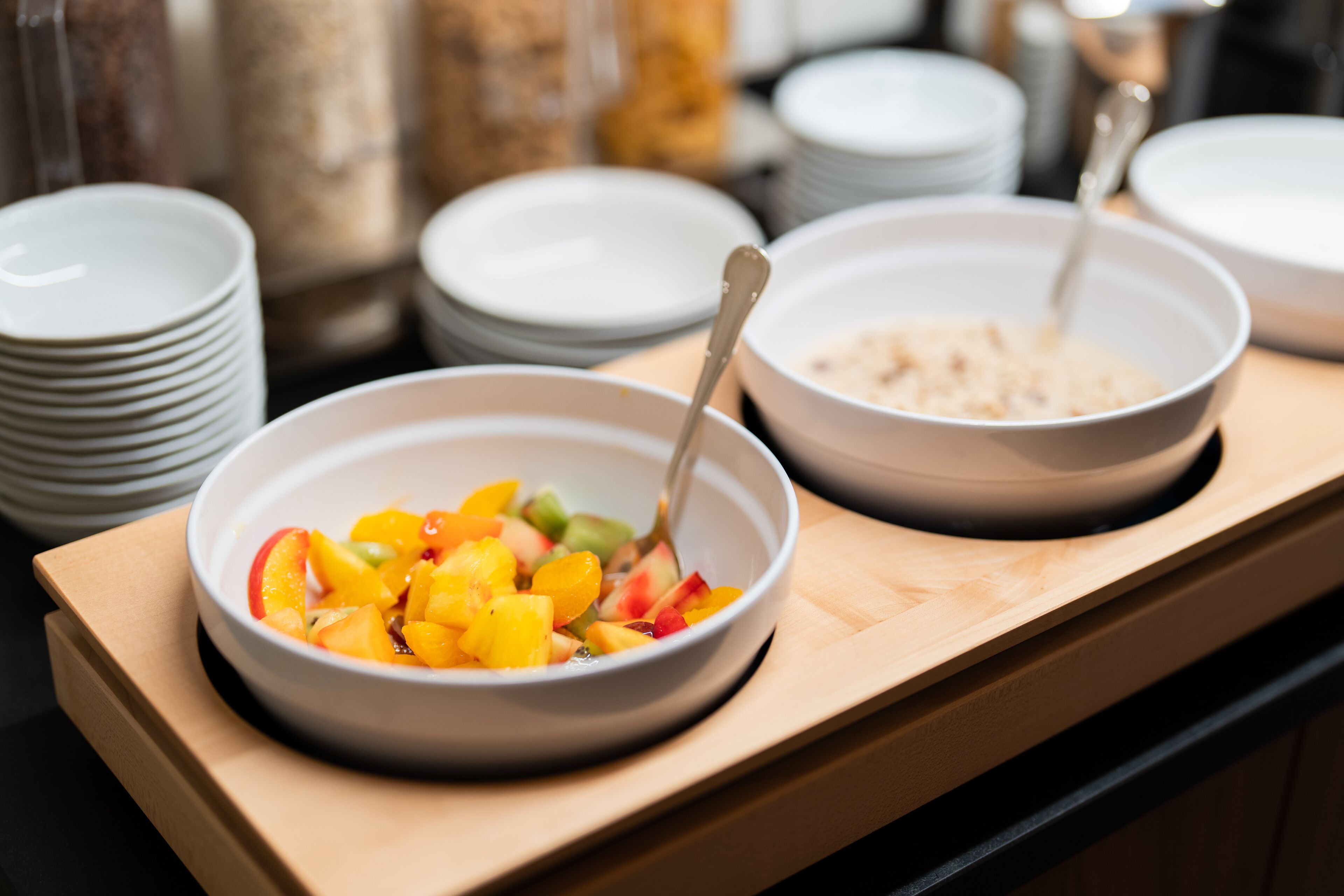 A breakfast buffet with bowls of fruit and cereal.