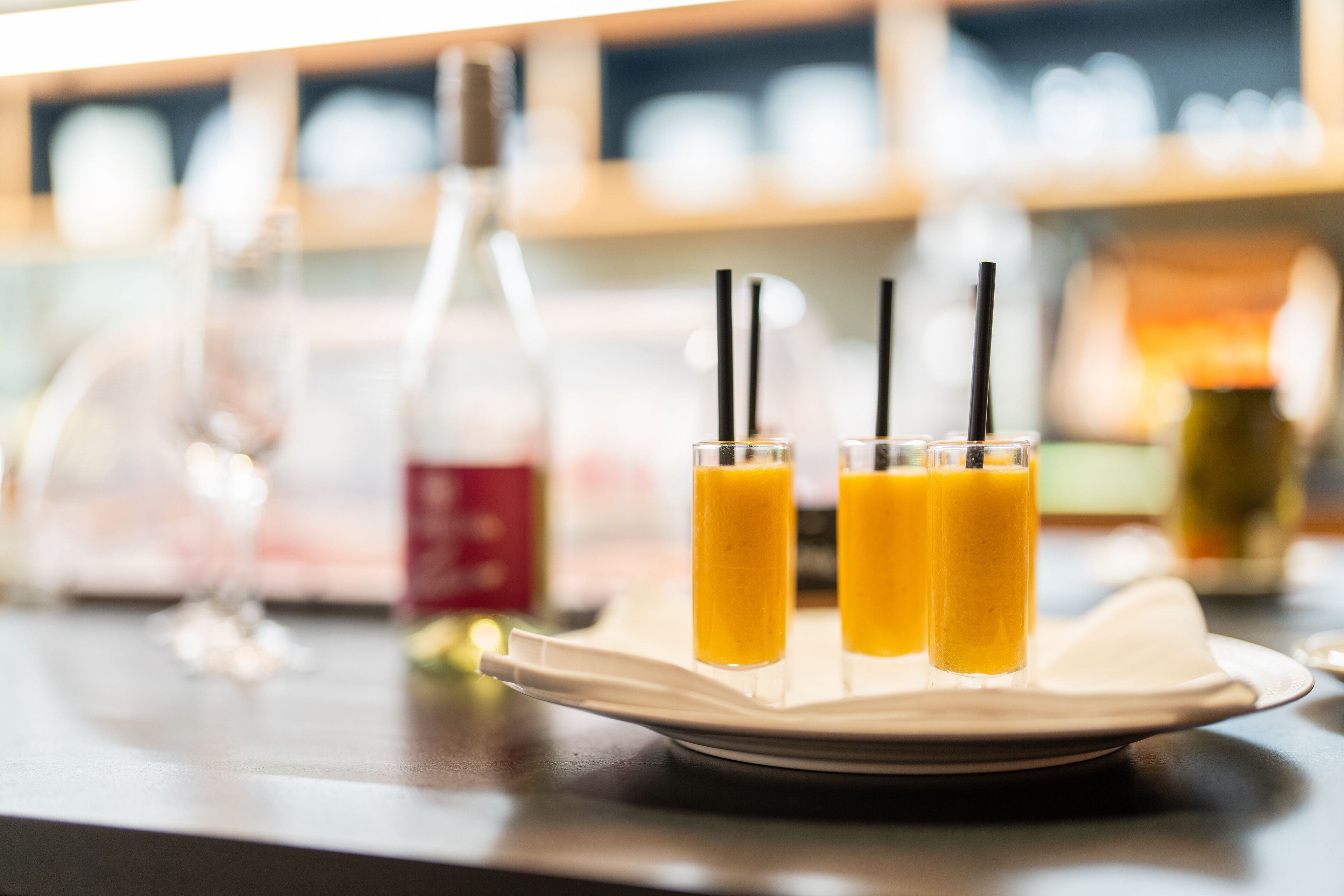 Ein Tablett mit drei Gläsern Orangensaft, einer Flasche und einem Glas auf einem Tisch.