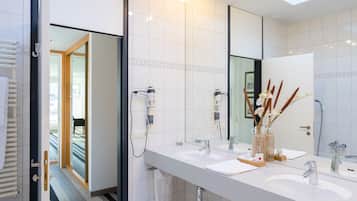 Un baño moderno con dos lavamanos, un espejo grande y un tragaluz.
