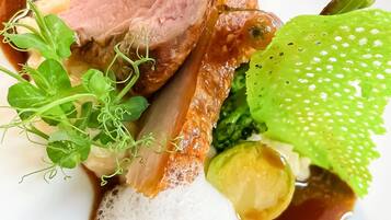 A plate with sliced meat, vegetables, and a frothy liquid.