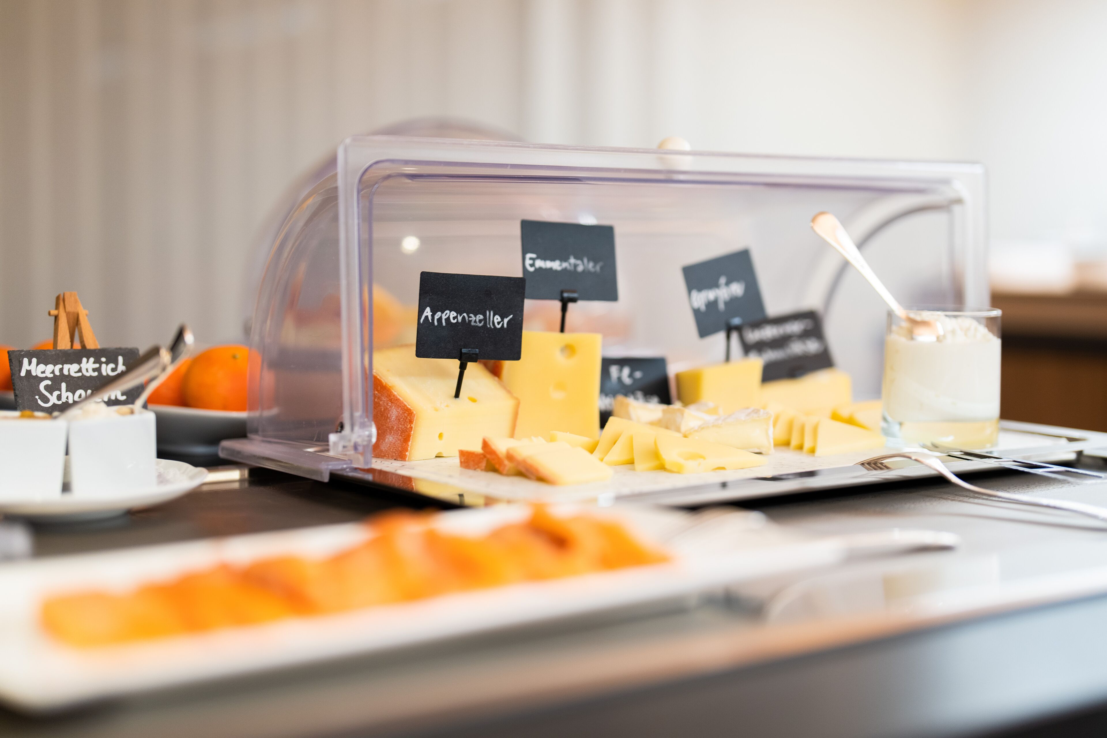 A buffet with various cheeses and a glass of milk.