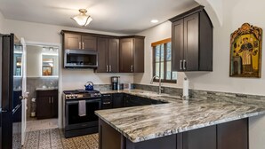 A modern kitchen with dark cabinets, a large island, and a decorative wall piece. - Casas de Suenos Old Town Historic Inn, an Ascend Collection Hotel (Albuquerque)