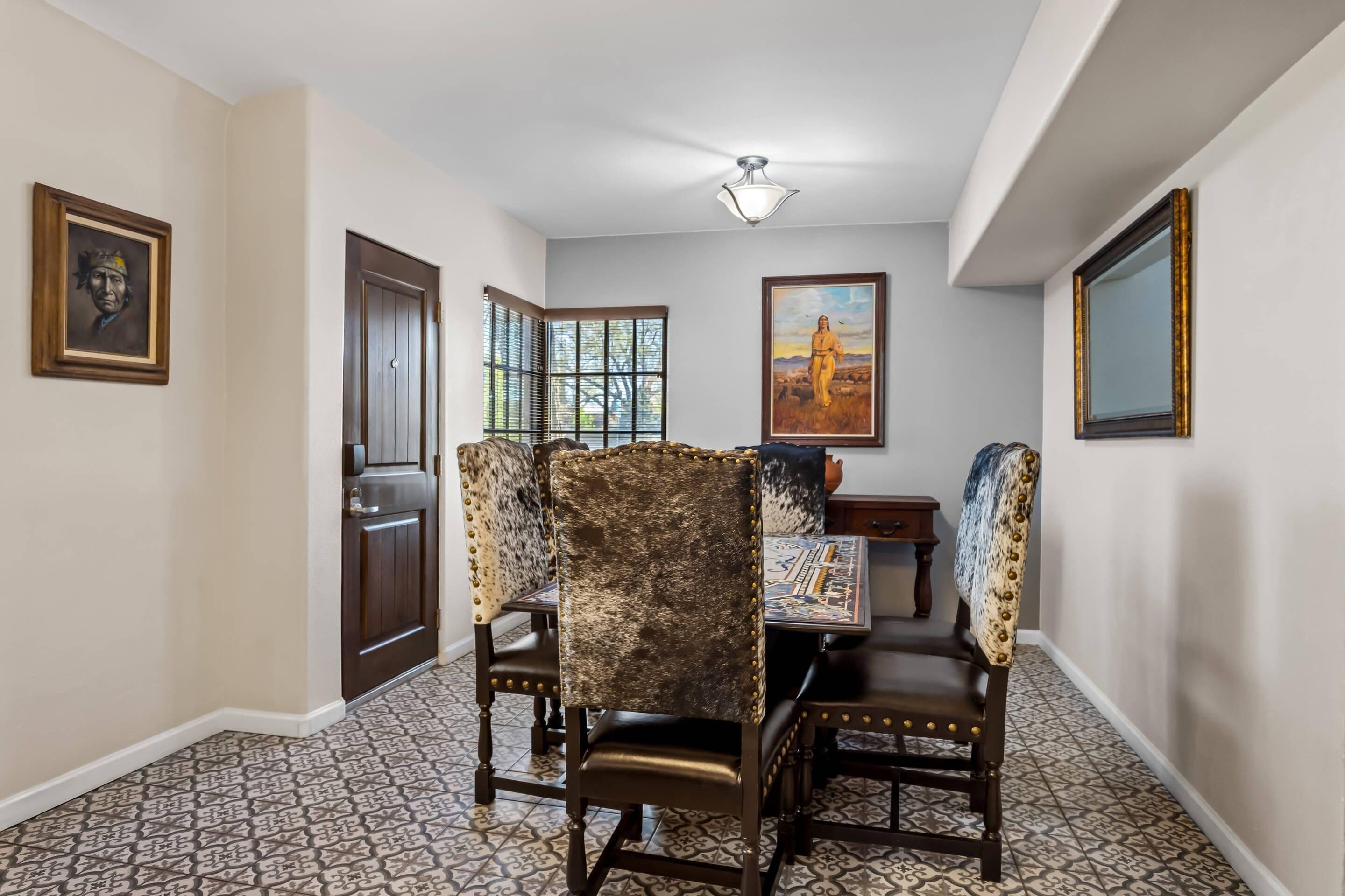 A dining area with patterned floor tiles, a table with chairs, and artwork on the walls.
