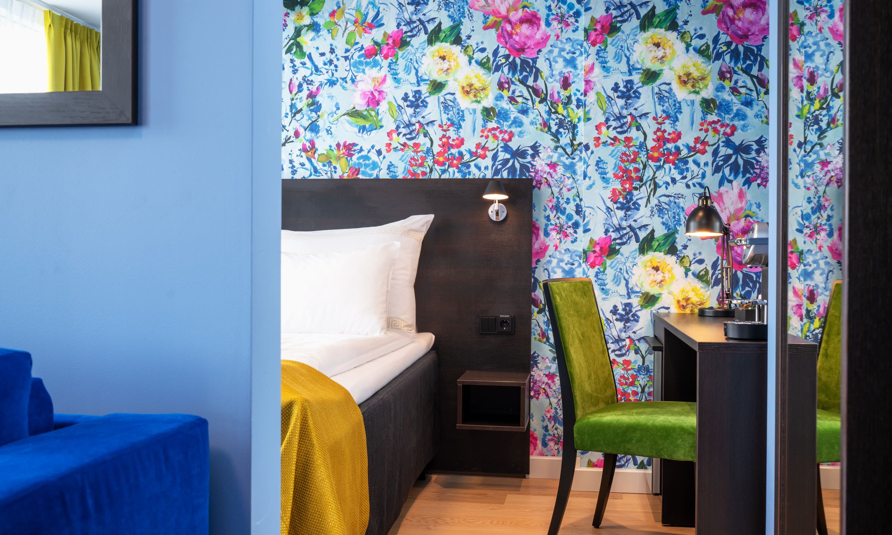 Ein Hotelzimmer mit einem Bett, einem Schreibtisch, einem Stuhl und einem Nachttisch.