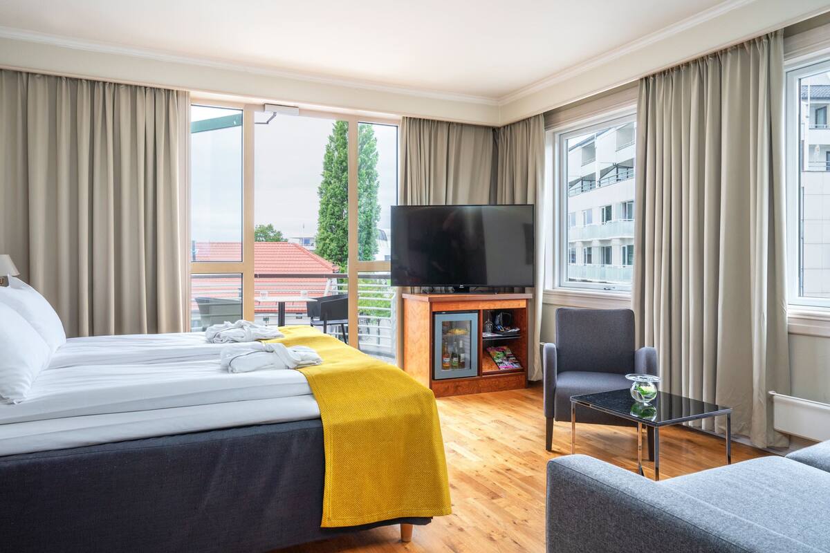 A hotel room with a bed, a TV, a small table, and a chair.