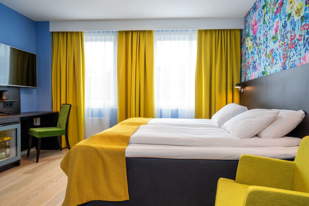A hotel room with a bed, a desk, a chair, and a TV.
