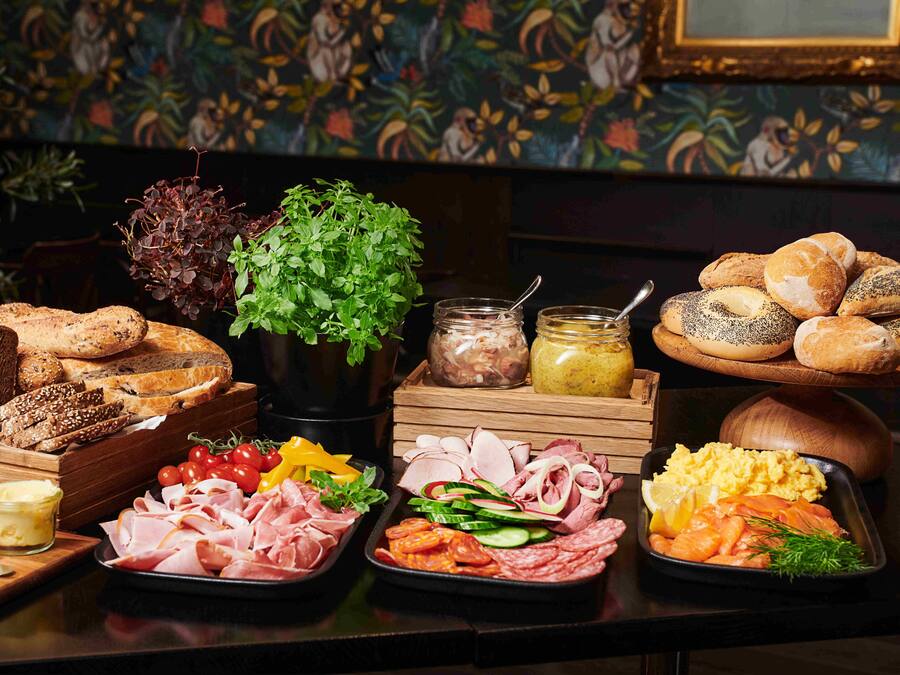 A buffet with various food items including bread, meats, vegetables, and condiments.
