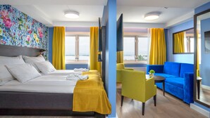 Une chambre d’hôtel avec un lit, un canapé, un fauteuil et une vue sur la mer.
