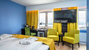 A hotel room with a bed, a desk, a television, and two chairs.