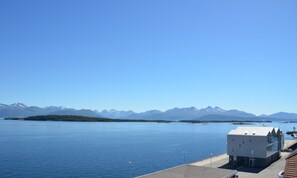 A coastal building with a view of a calm sea and distant mountains.