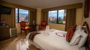 Una habitación de hotel con una cama grande, dos sillas, un escritorio y vistas a la ciudad.