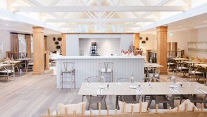 Un comedor amplio con barra central, mesas y sillas de madera.