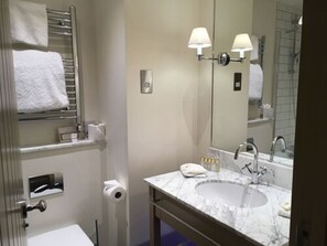 A bathroom with a marble sink, a mirror, a towel rack, and a toilet paper holder. - Champneys Forest Mere (Liphook)
