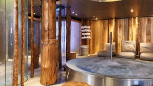 Habitación de spa con jacuzzi, paredes de madera y zona de estar.