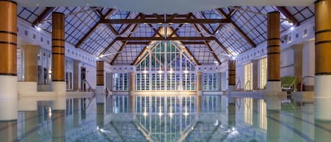 Una piscina cubierta, una piscina al aire libre, tumbonas