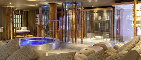 Un área de spa moderna con un jacuzzi, asientos con cojines estampados y una zona de ducha con paredes de vidrio.