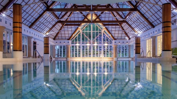 Una piscina interior con techos altos y ventanas amplias.
