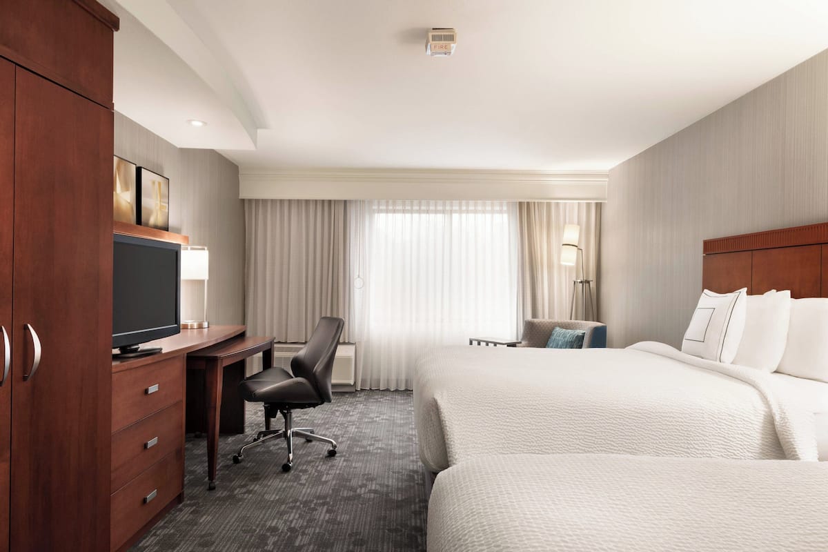 Une chambre d’hôtel avec un lit, un bureau avec un ordinateur, une chaise et un téléviseur.