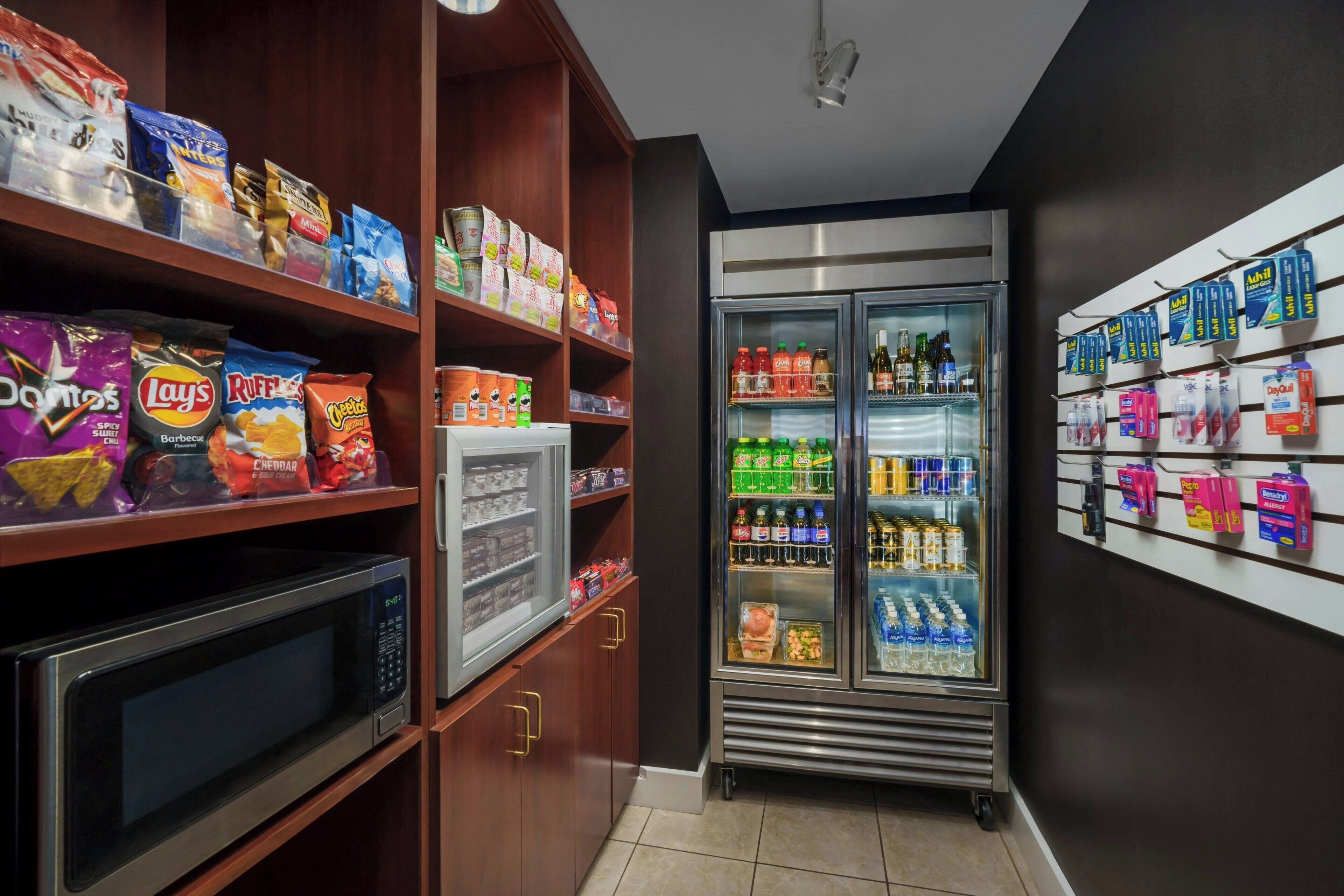 Ein Bereich mit Snacks und Getränken, inklusive Mikrowelle, Kühlschrank und Regalen voller Verpflegung.