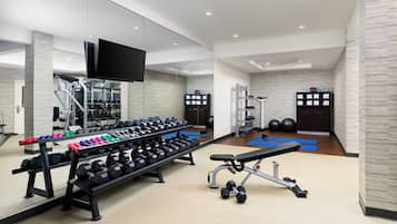 A modern gym with weightlifting equipment, exercise mats, and a bench.