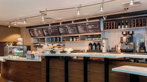 Een moderne bar met een menubord, bargedeelte en diverse drankjes en snacks.