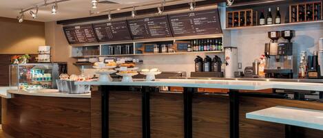 A modern bar area with a menu board, bar counter, and various beverages and snacks.