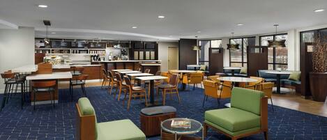 A modern hotel lobby with a bar area, seating arrangements, and large windows providing natural light.
