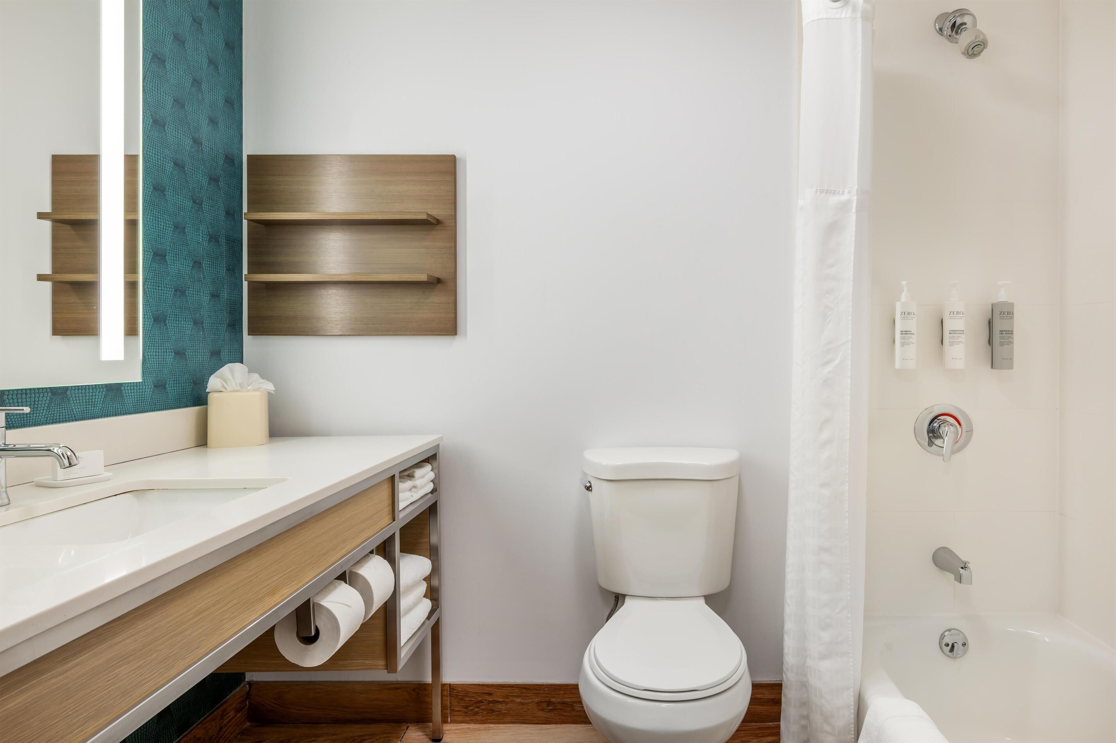 Casa de banho moderna com uma sanita branca, uma loiça sanitária e uma área de chuveiro.